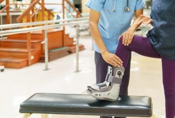 Physical therapist checks the patient's knee in the clinic. Because of pain while wearing orthopedic boot, walking training. medical and orthopedic